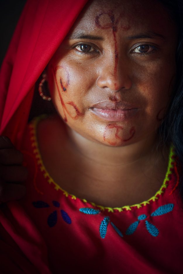 Woman with traditional face markings and red veil.