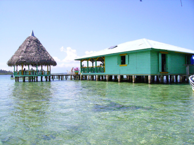 Bungalow tropical sur l'eau avec toit de chaume.