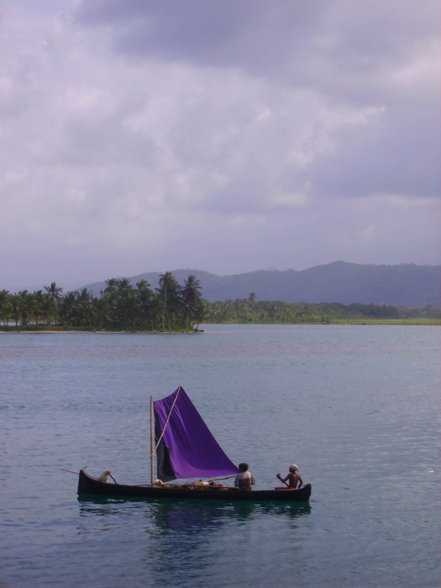 Bateau traditionnel naviguant près d'une île tropicale