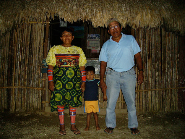 Famille en vêtements traditionnels et modernes à l'extérieur de la hutte.