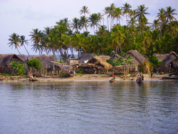 Village de plage tropical avec des palmiers et des huttes en chaume.