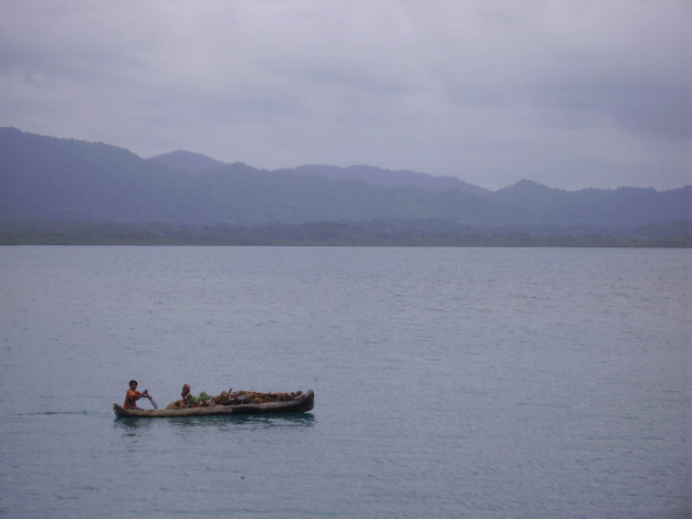 Deux personnes pagayant en canoë sur un lac serein avec des montagnes.