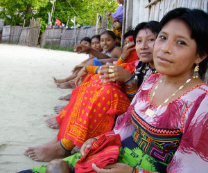 Group of people sitting on sandy beach.