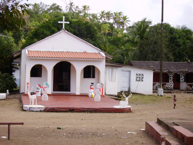 Petite église rurale avec des décorations de Noël dans un cadre tropical.