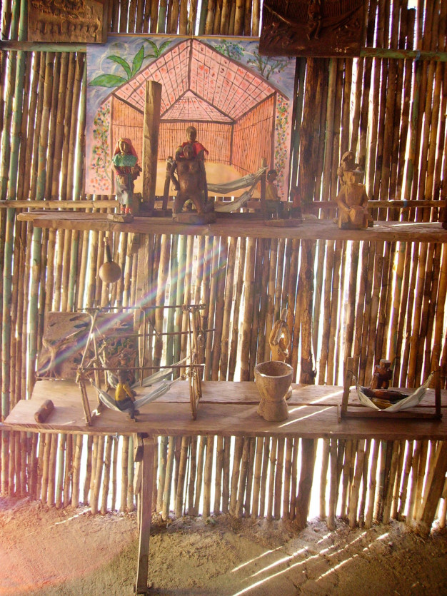 Objets traditionnels en bois exposés à l'intérieur d'une structure en bambou.