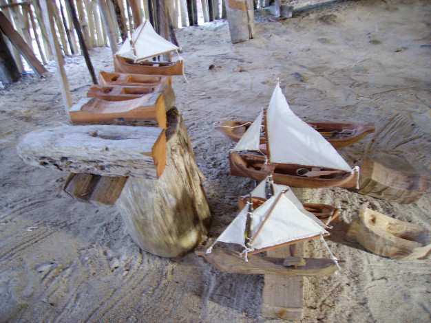 Voiliers jouets en bois exposés sur le sable.
