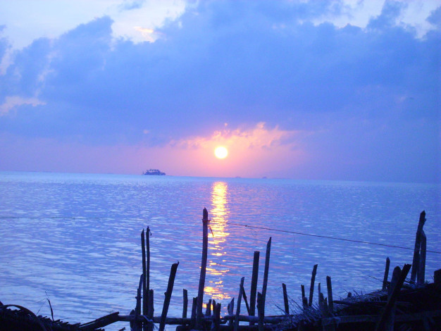 Coucher de soleil sur un océan tranquille avec silhouette d'un quai en bois.