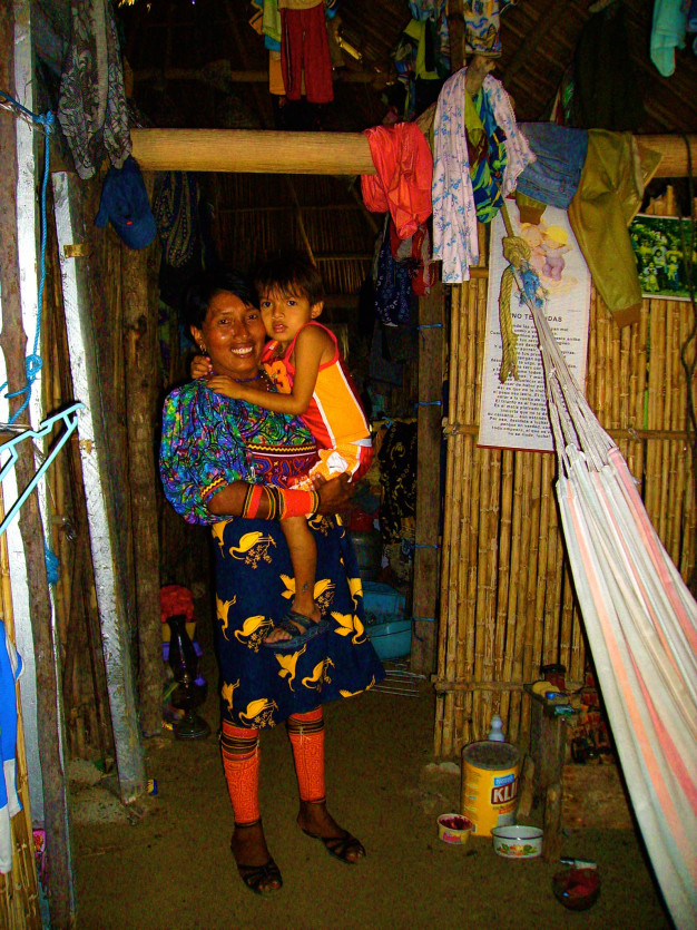 Femme tenant un enfant dans un intérieur traditionnel.