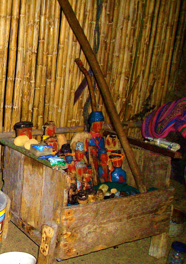 Objets traditionnels en bois et textiles à l'intérieur de la hutte.