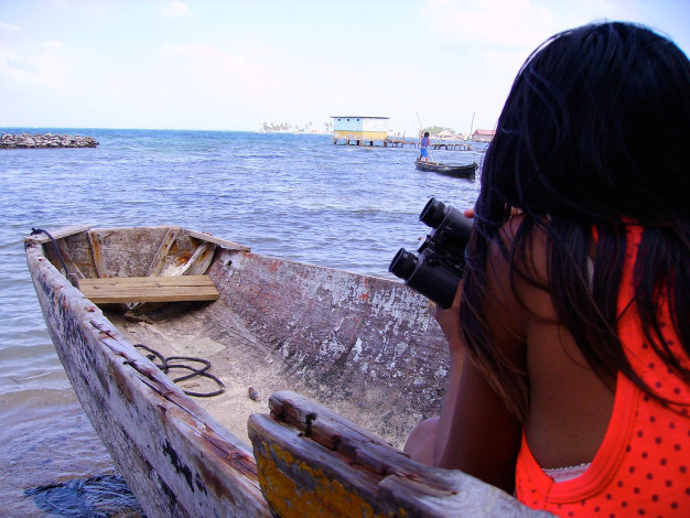 Femme avec jumelles sur un bateau, regardant la mer.
