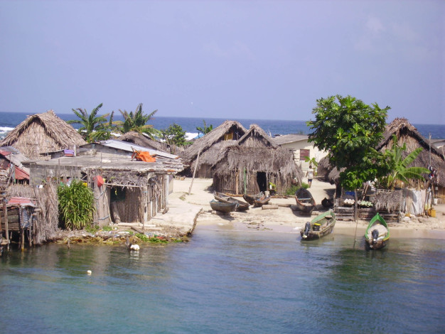 Village côtier rustique avec cabanes au toit de chaume et bateaux