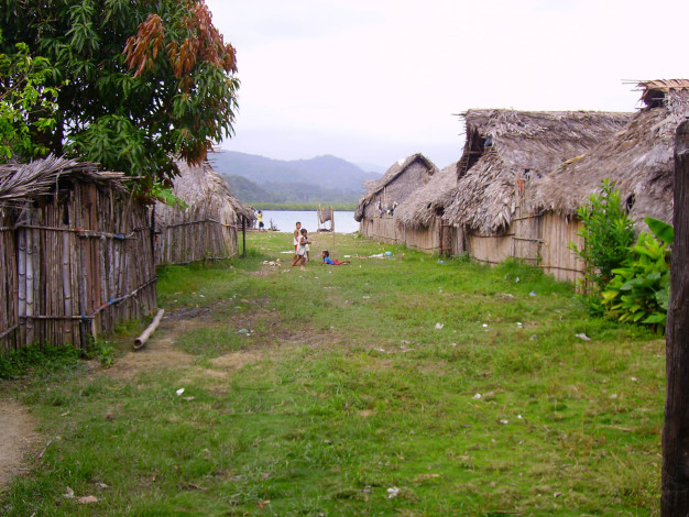 Village rural avec des huttes traditionnelles et des enfants jouant à l'extérieur.