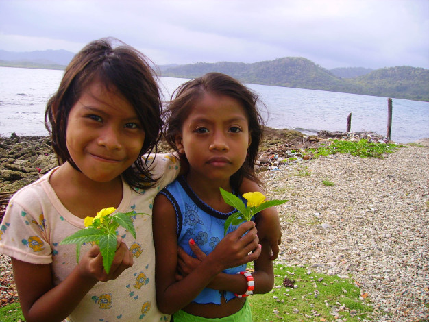 Deux jeunes filles tenant des fleurs au bord d'un lac.