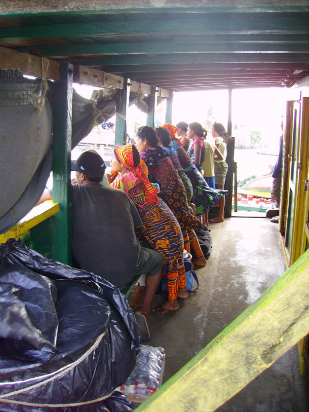 Passagers attendant dans le bateau avec des vêtements colorés.