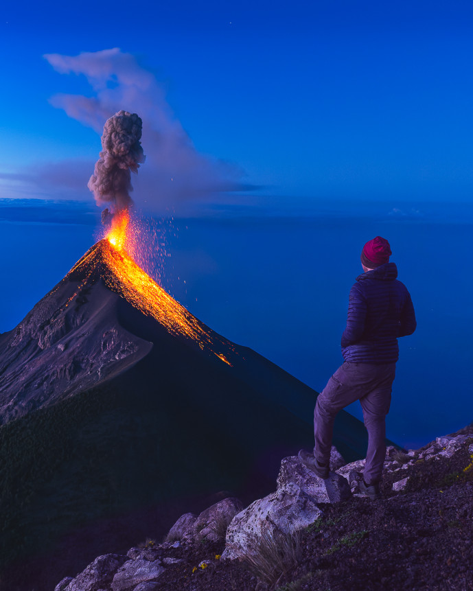 Personne observant une éruption volcanique au crépuscule