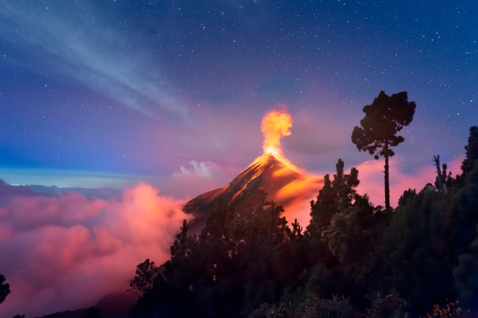 Éruption volcanique de nuit sous un ciel étoilé.