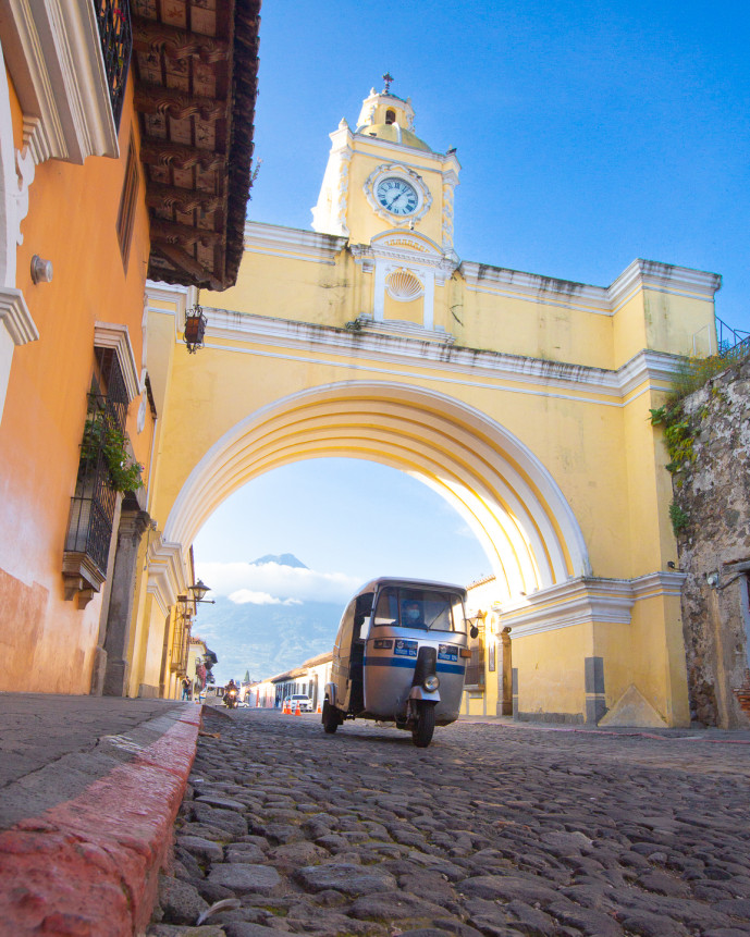 Tuk-tuk sous une arche historique avec la montagne en arrière-plan.