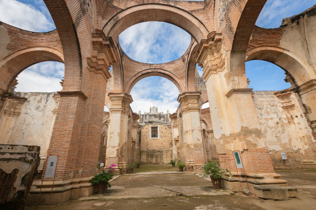 Ruins of ancient brick church with arches and sky.