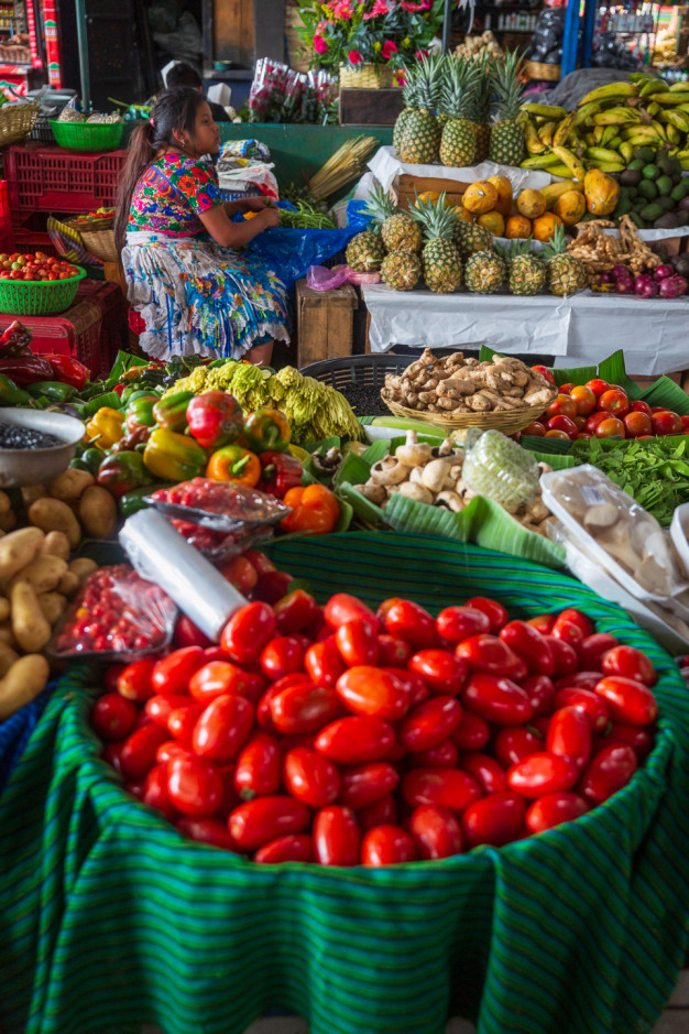 Woman at colorful fruit and vegetable market stall.