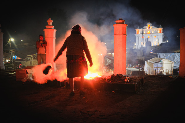Person near fire and smoke at night festival.