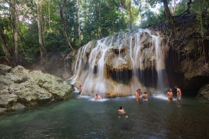 Des personnes se baignent dans une cascade de forêt tropicale.