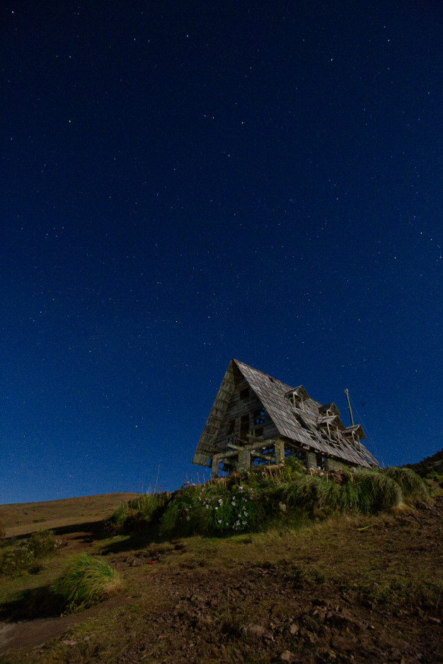 Starry night sky over abandoned wooden house.