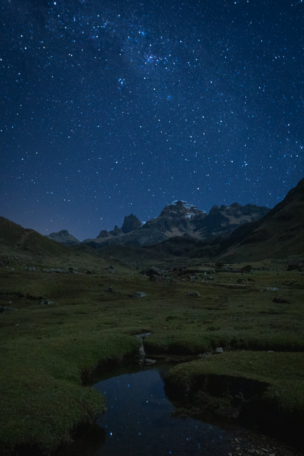 Starry night sky over a tranquil mountain landscape.