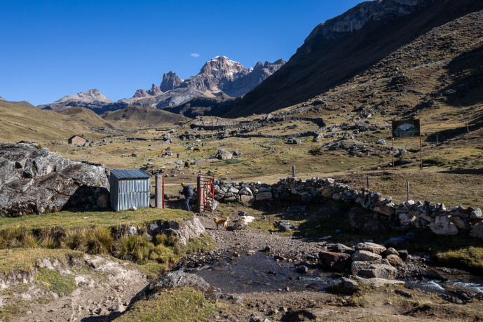 Mountainous landscape with hut and grazing animals.