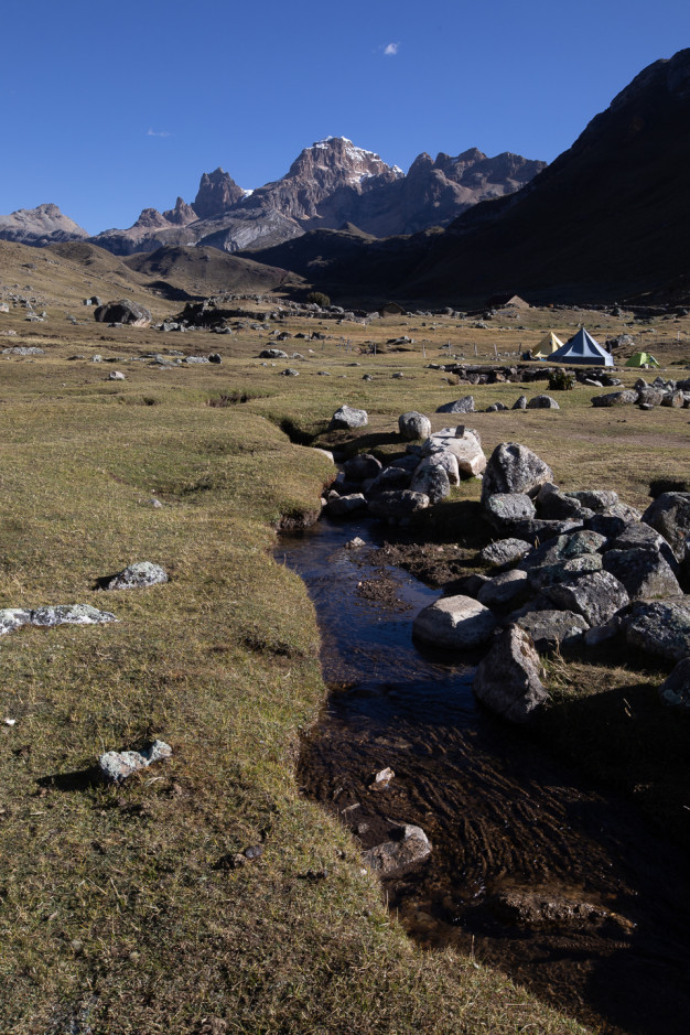 Mountain stream with tents and rocky landscape