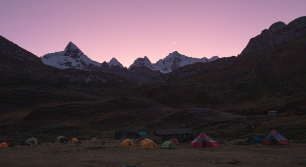 Twilight at mountain base camp with tents.