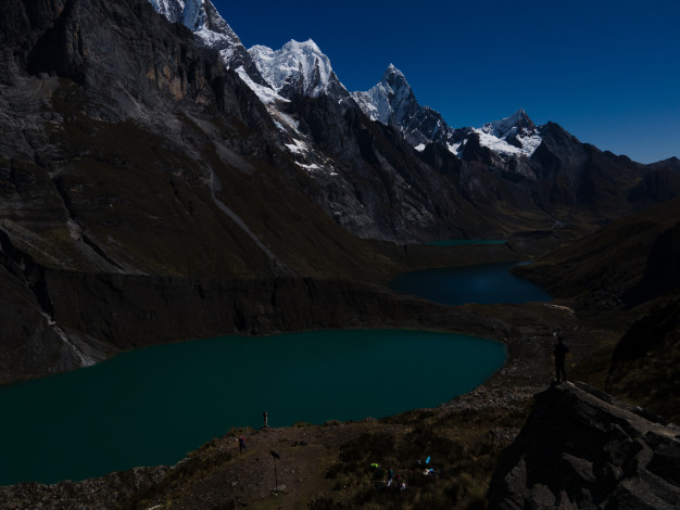 Paysage montagneux avec des lacs turquoise et des randonneurs.