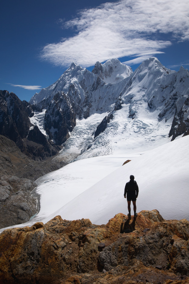 Hiker facing snowy mountain landscape under blue sky