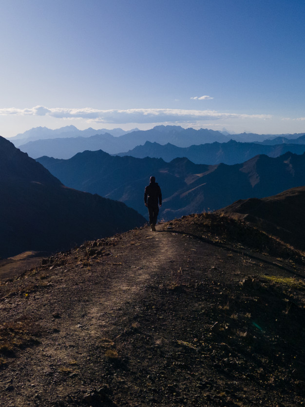 Hiker silhouetted against mountain range at sunset.