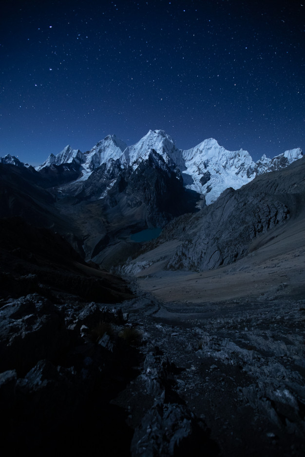 Nuit étoilée sur un paysage de montagne enneigée et un lac alpin.