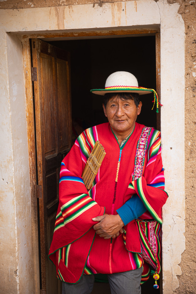 Homme en tenue traditionnelle andine avec flûte de pan.
