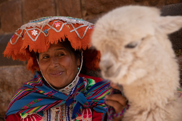 Peruvian woman smiling with baby alpaca.