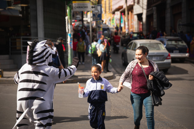 Person in zebra costume high-fiving child on street.