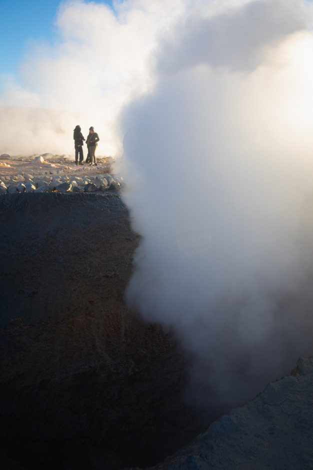 People observing steam at geothermal site.