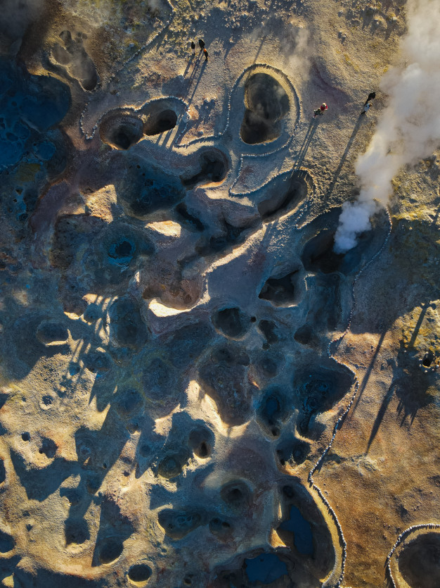 Vue aérienne d'une zone géothermique avec des cheminées de vapeur.