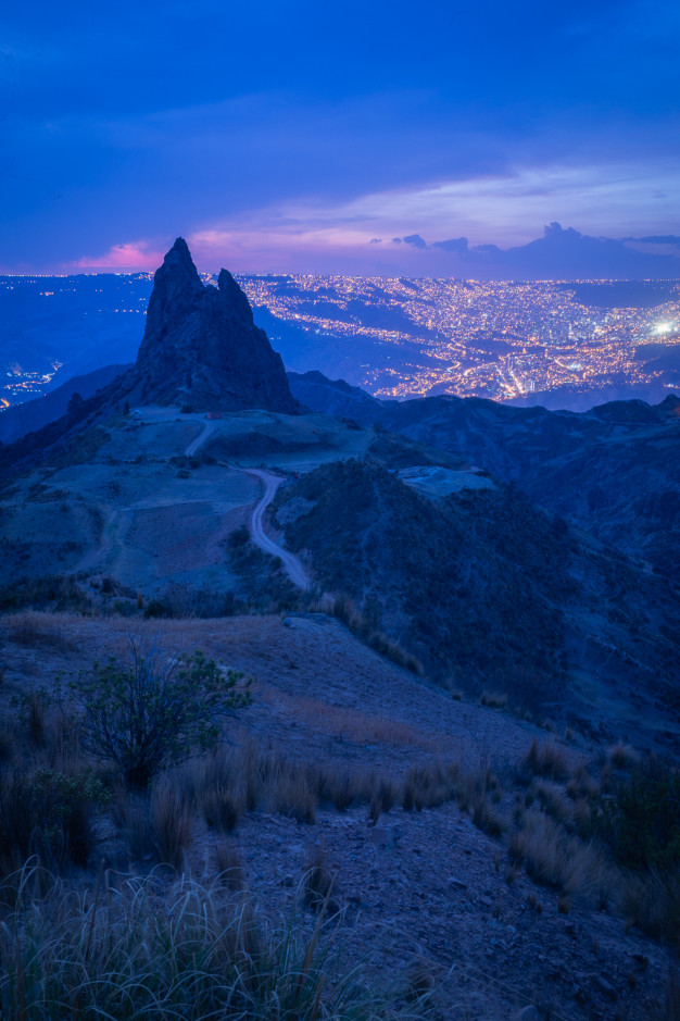 Paysage montagneux au crépuscule avec vue sur les lumières de la ville.