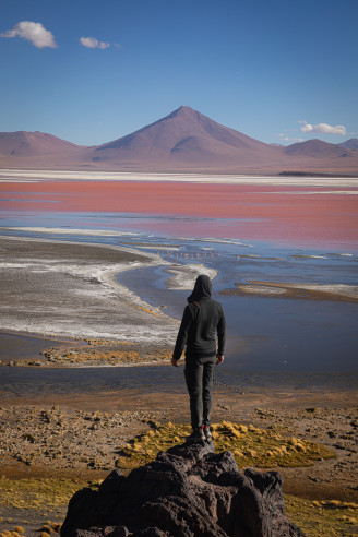 text-center Person overlooking red lagoon and mountain landscape.