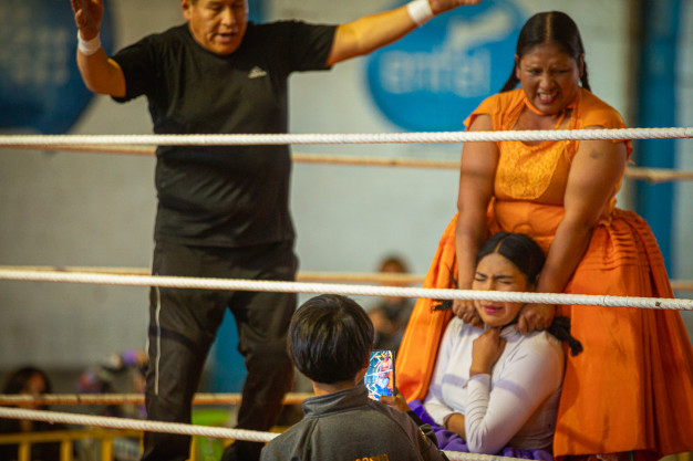 Wrestling match with referee and female wrestlers in action