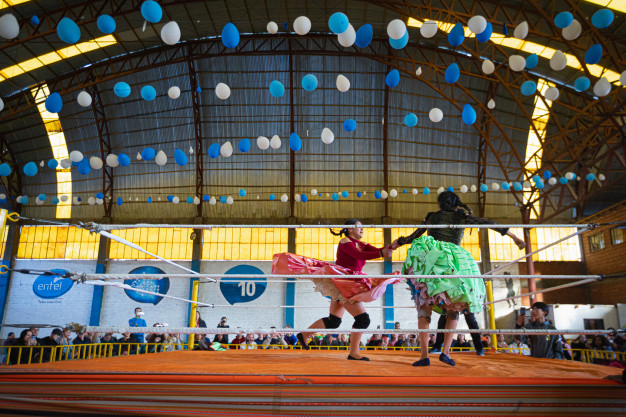 Indoor wrestling match with colorful balloons and spectators