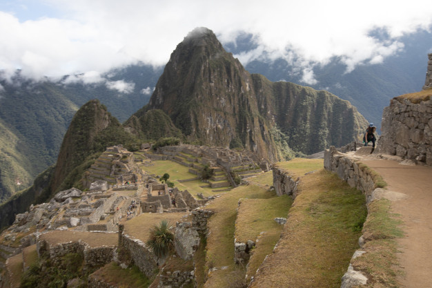 Machu Picchu ruins with visitors and foggy mountains.