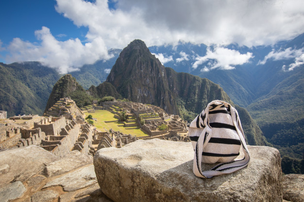 Sac à dos surplombant les ruines du Machu Picchu sous un ciel ensoleillé.
