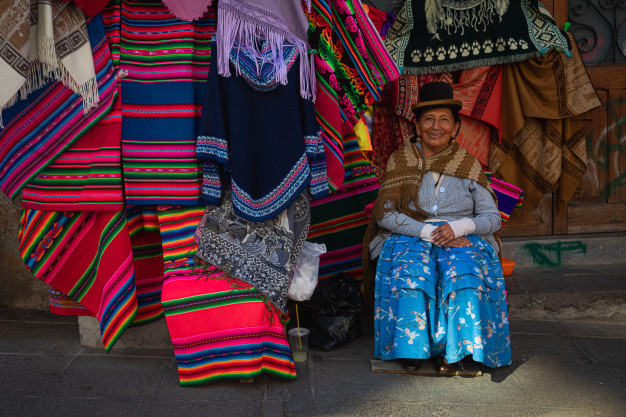 Woman selling colorful textiles on street.