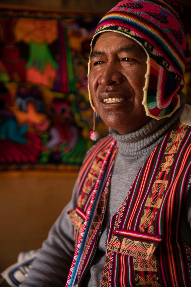 Man in traditional Andean clothing smiling.