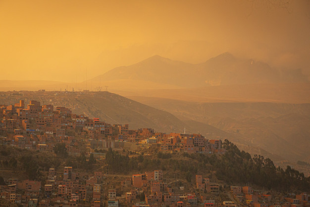 Coucher de soleil doré sur un paysage urbain montagneux.