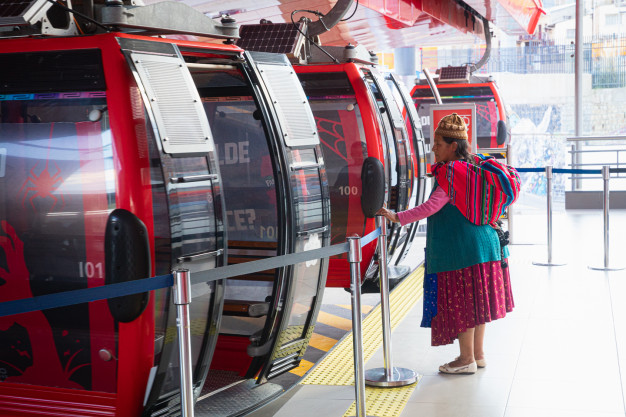 Femme montant à bord d'une cabine de téléphérique rouge.