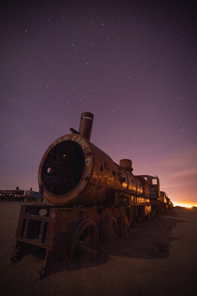 Abandoned train under starry sky at twilight.